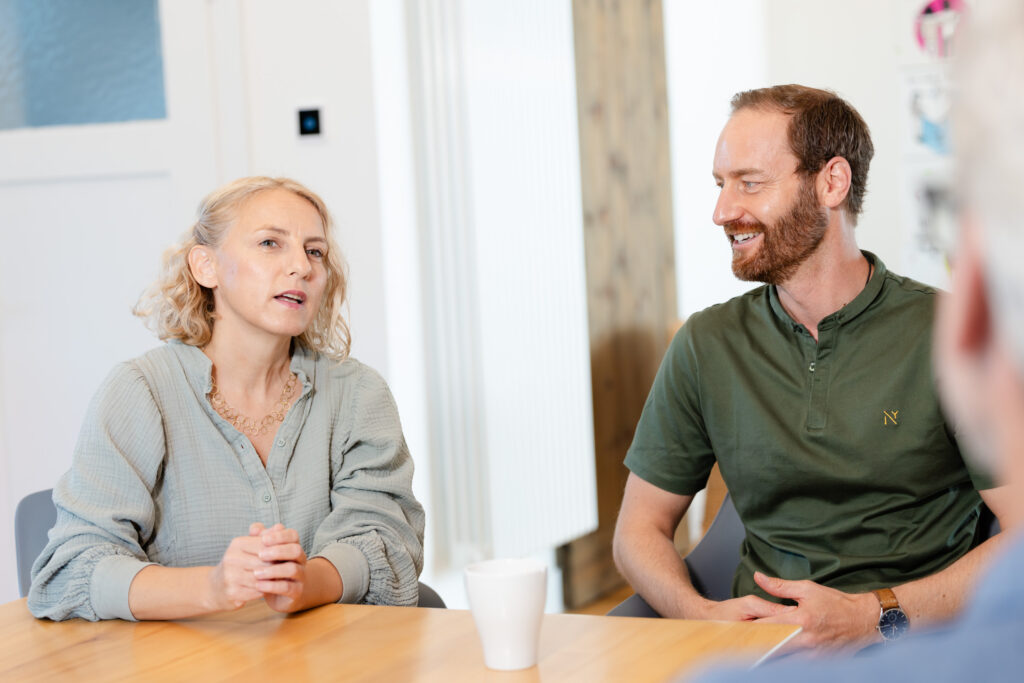 Mandy Geisler und Sven von der Heyde sitzen an einem Holztisch während des Interviews zum Thema psychologische Sicherheit