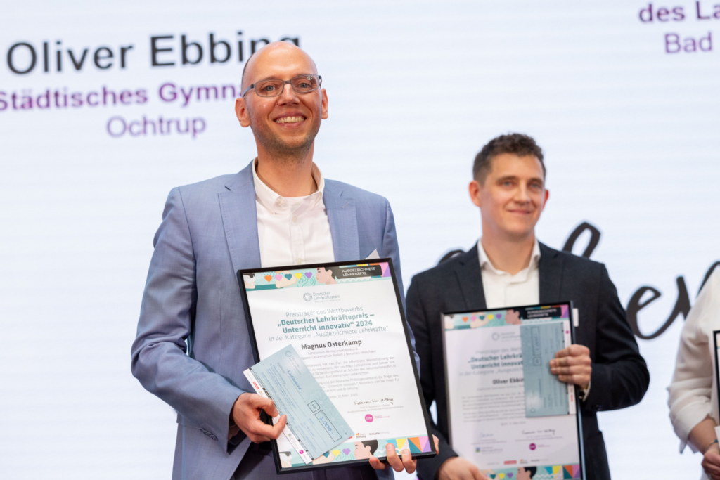 Magnus Osterkamp erhält den Deutschen Lehrkräftepreis 2024. Er hält die Urkunde hoch.